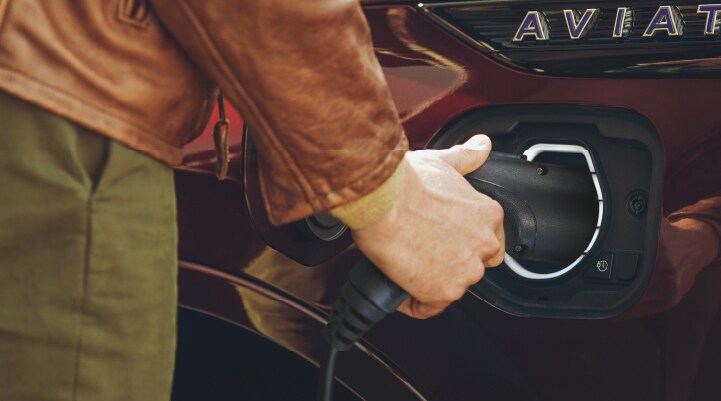 A hand is shown plugging in the charger into the charging port of a 2021 Lincoln Aviator