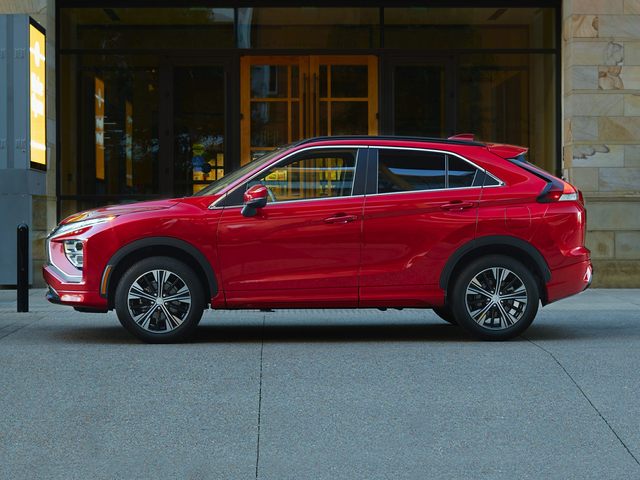 Mitsubishi Eclipse Cross with a red exterior outside a stone building with wooden door
