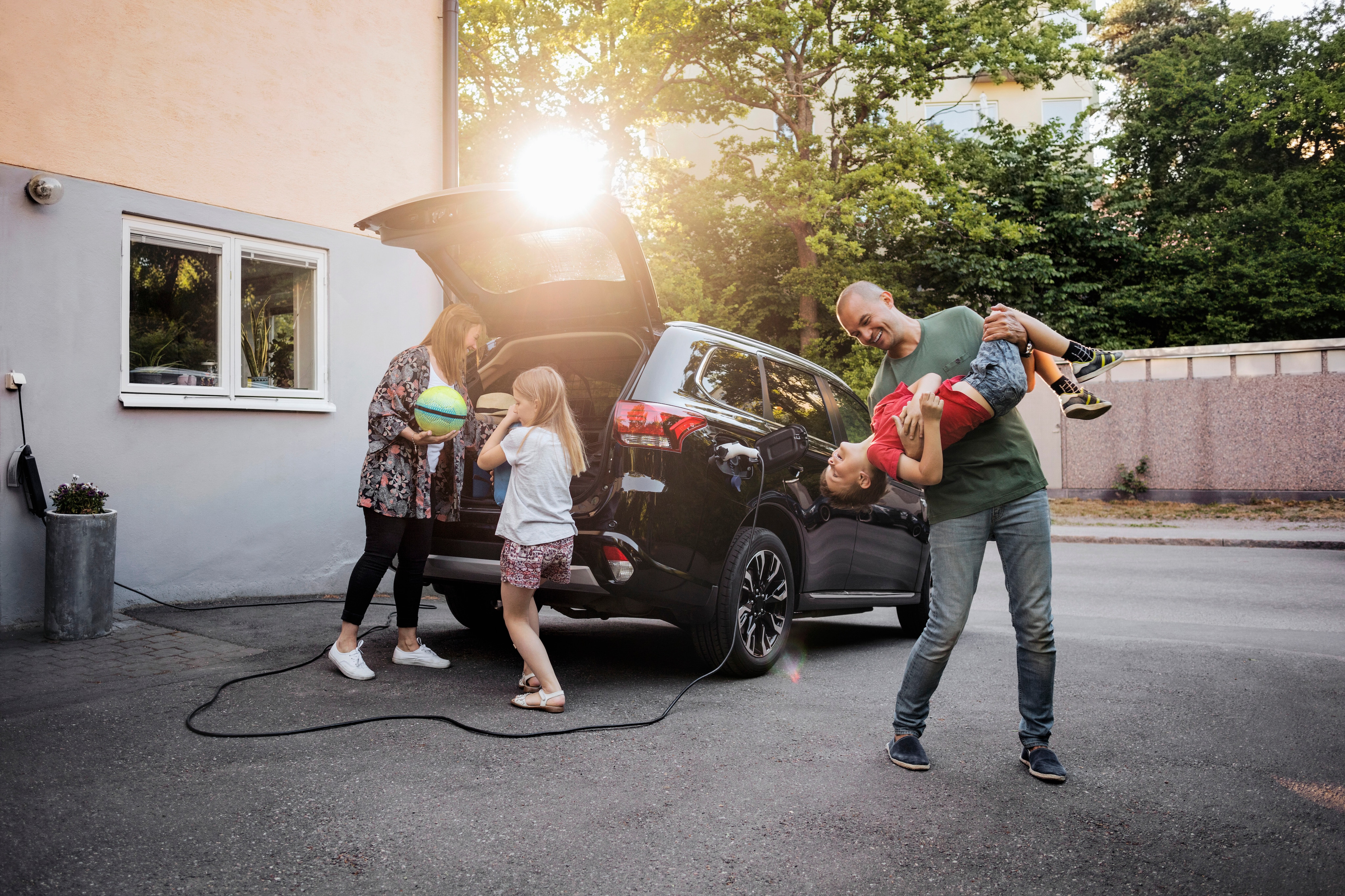 Family having fun with 2 children and electric vehicle in the background
