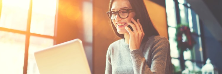 A woman on a phone call and searching for a car on her laptop