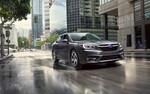 A 2021 Subaru Legacy driving on a rainy city street.