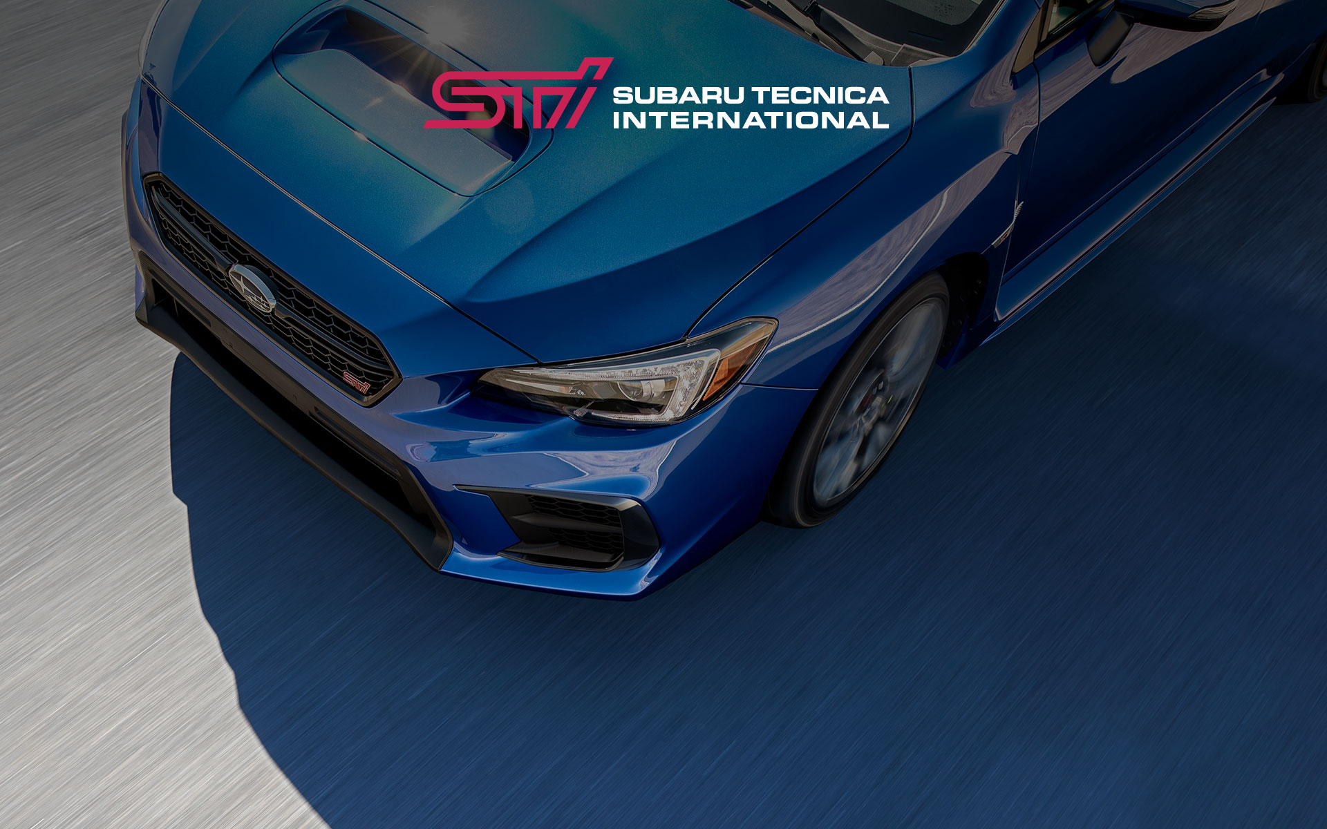 Subaru Tecnica International logo and overhead view of 2019 WRX STI