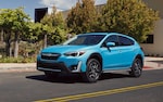 A 2021 Crosstrek Hybrid driving down a highway road.