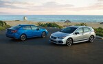 A photo of a 2021 Impreza 5-door and sedan parked in front of a beach.