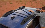 A man setting up the standard raised roof rails on a 2021 Subaru Outback.